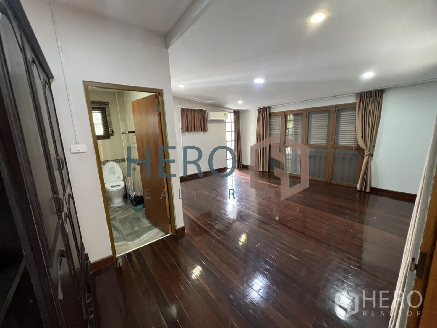 Detached House for rent in Watthana, Bangkok - Bedroom with wood floors, built-in furniture and an ensuite entrance.