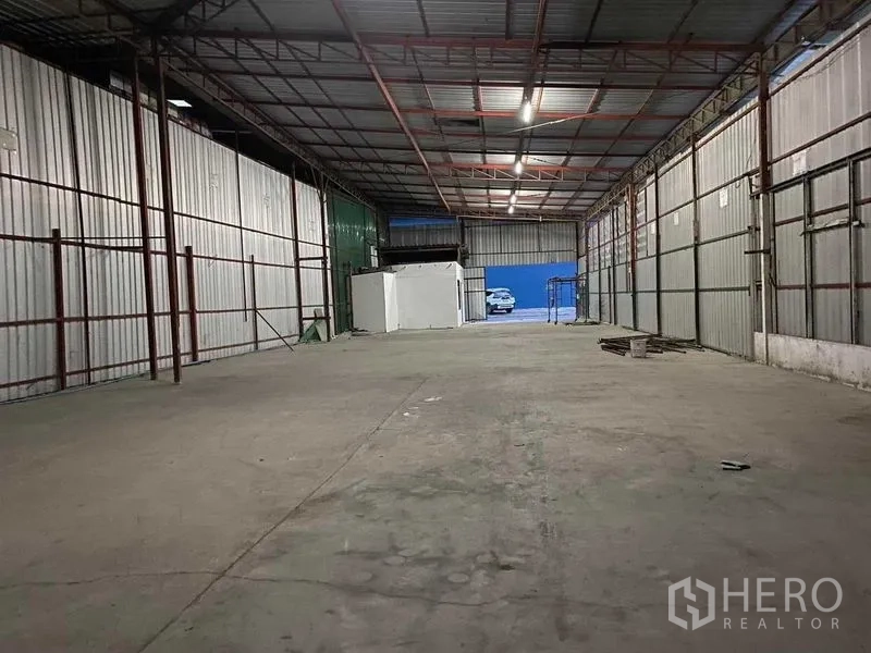 Warehouse for rent in Saphan Sung, Bangkok - Open warehouse interior with high steel truss roof, bright lighting, and durable concrete floor for storage.