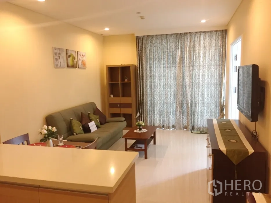 Condominium for rent or sale in Khlong Toei, Bangkok - Cozy living area with sofa, coffee table, media console and full-length patterned curtains.