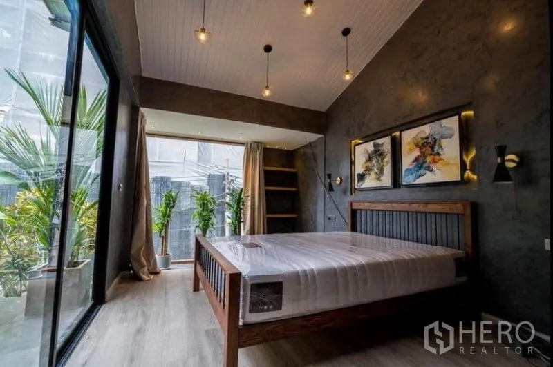 Townhouse for rent in Khlong Toei, Bangkok - Bright bedroom with high ceiling, pendant lights, sliding glass door and indoor plants.