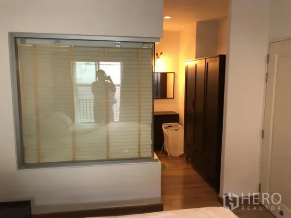 Condominium for rent in Pathum Wan, Bangkok - Bedroom with large wardrobe, dressing area and an interior window with blinds.