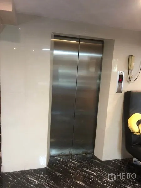 Shophouse for rent in Bang Rak, Bangkok - Closed stainless-steel elevator doors in a glossy lobby.
