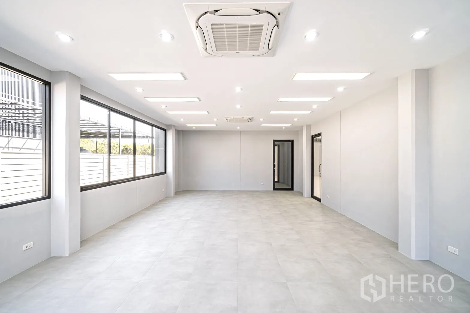 Factory for rent or sale in Lam Luk Ka, Pathum Thani - Large office area with full-length windows, recessed lighting and neutral finishes.