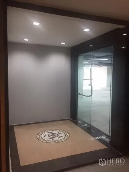 Office Space for rent in Watthana, Bangkok - Lobby entrance to the office with recessed lights, decorative tiled medallion, and glass door.