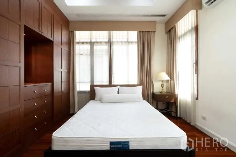 Detached House for rent in Watthana, Bangkok - Bedroom with built-in wooden wardrobes, large windows and bed.