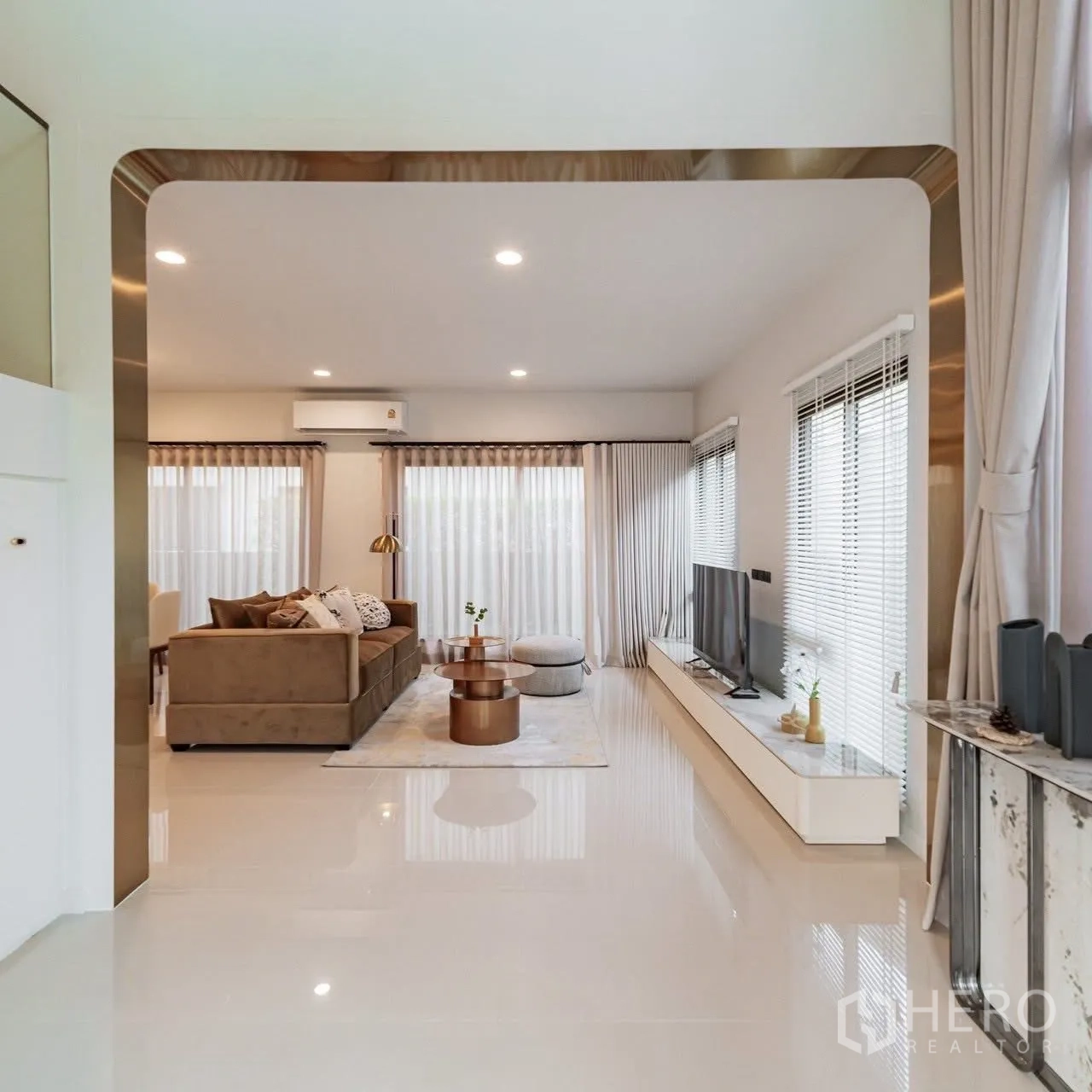 Detached House for sale in Bang Kapi, Bangkok - Open-plan living room with L-shaped sofa, TV console, large windows and glossy tiled floors in a modern Bang Kapi home.