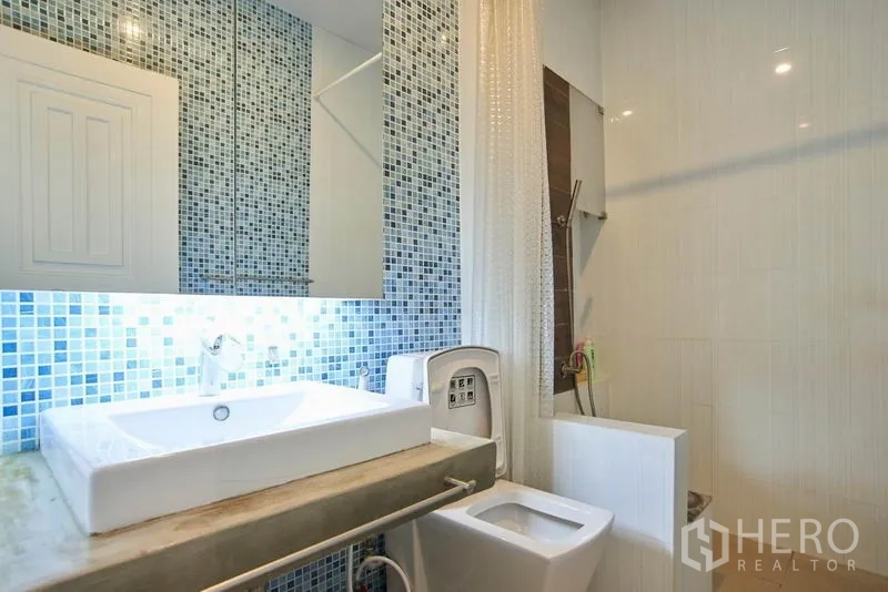 Home Office for rent in Wang Thonglang, Bangkok - Bright bathroom with blue mosaic accent wall, square basin and shower area.
