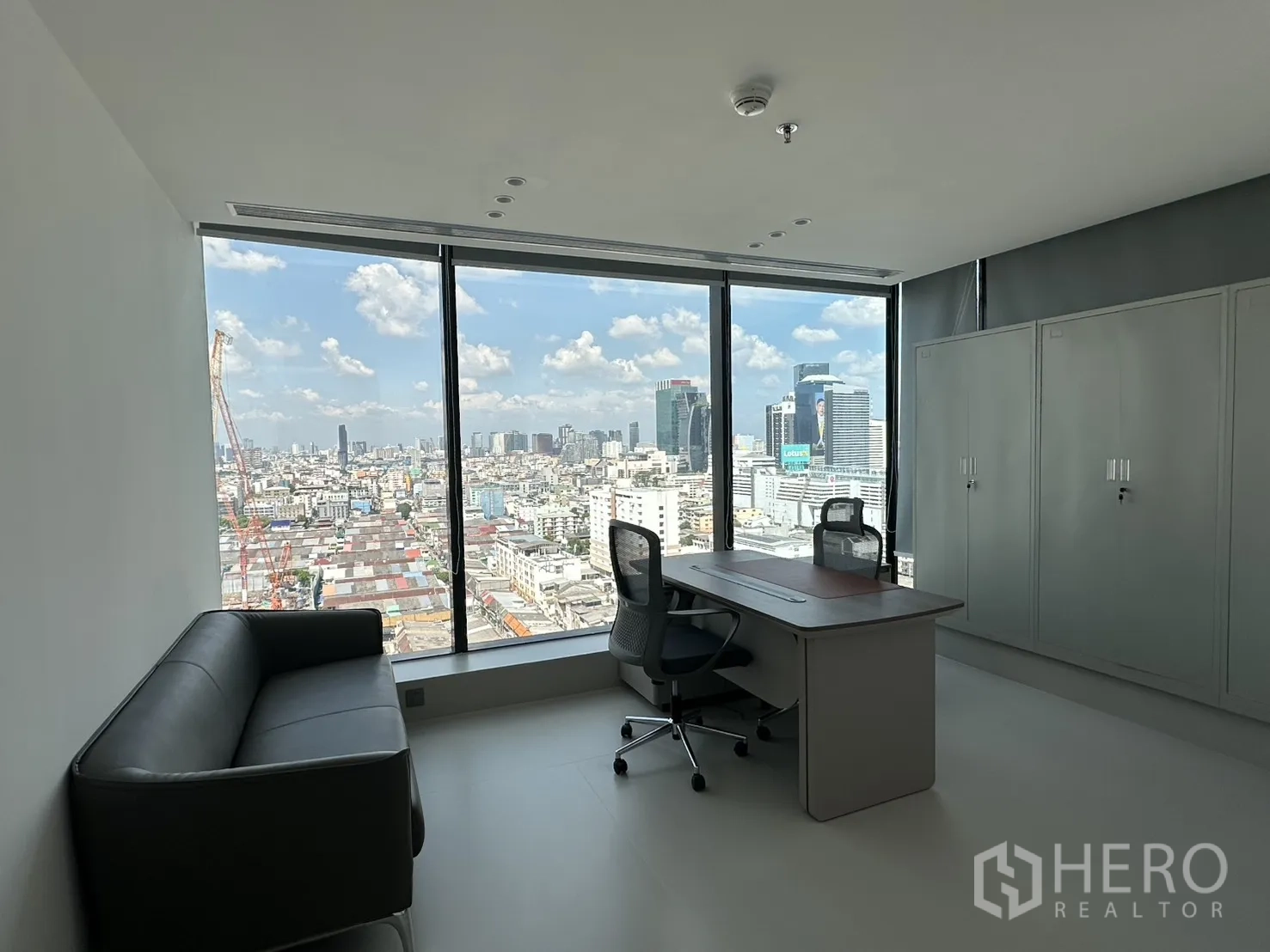 Office Space for rent in Din Daeng, Bangkok - Private office with desk, chair, sofa, storage cabinets, and floor-to-ceiling windows overlooking the city.