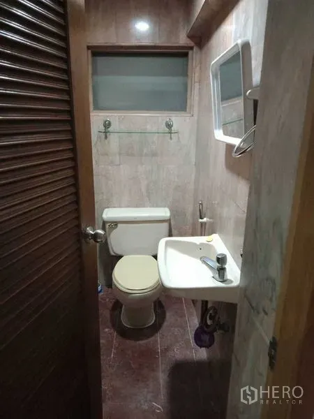 Townhouse for rent in Khlong Toei, Bangkok - Compact guest bathroom with toilet and pedestal sink.