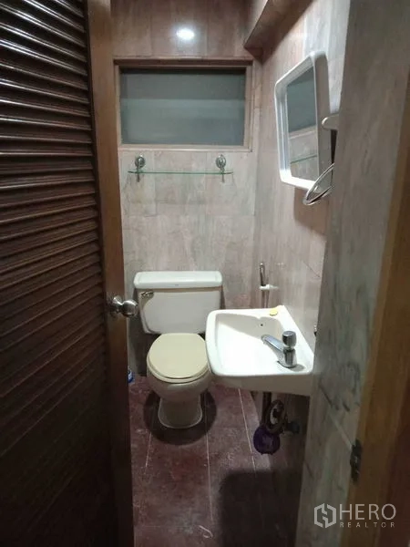 Townhouse for rent in Khlong Toei, Bangkok - Compact guest bathroom with toilet and pedestal sink.