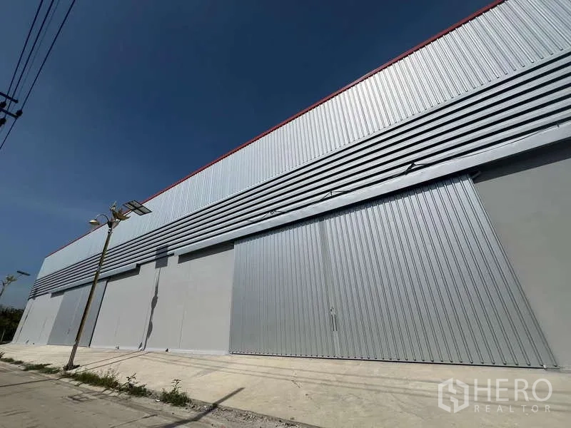 Warehouse for rent in Prawet, Bangkok - Long elevation of warehouse with oversized sliding doors and upper ventilation panels.