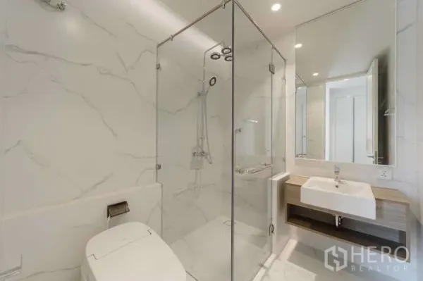 Townhouse for rent or sale in Watthana, Bangkok - Bright bathroom featuring a glass-enclosed shower, smart toilet, and wall-mounted vanity.