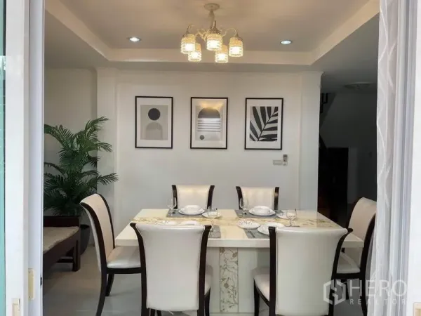 Detached House for rent in Suan Luang, Bangkok - Dining room with marble-top table for six, pendant chandelier and framed wall art.