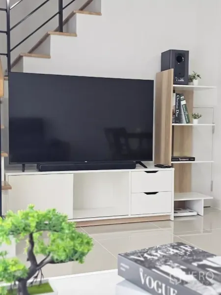Townhouse for rent in Bang Phli, Samut Prakan - Living room with 55-inch smart TV on a white console beside an open staircase.