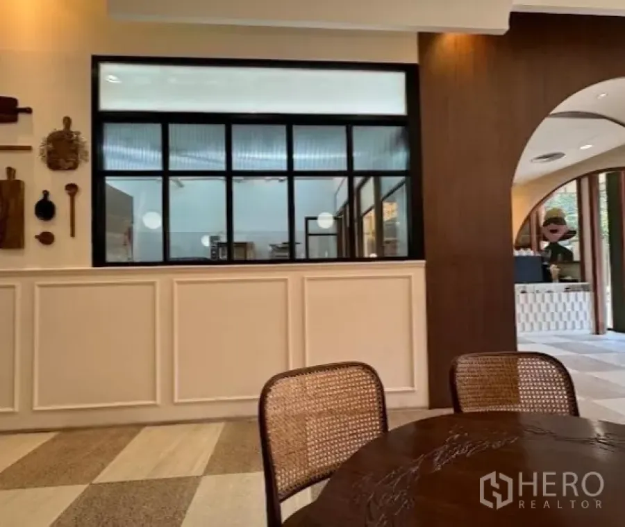 Retail Space for rent in Watthana, Bangkok - Warm cafe-style interior with black-framed window, paneled wall, and rattan chairs.