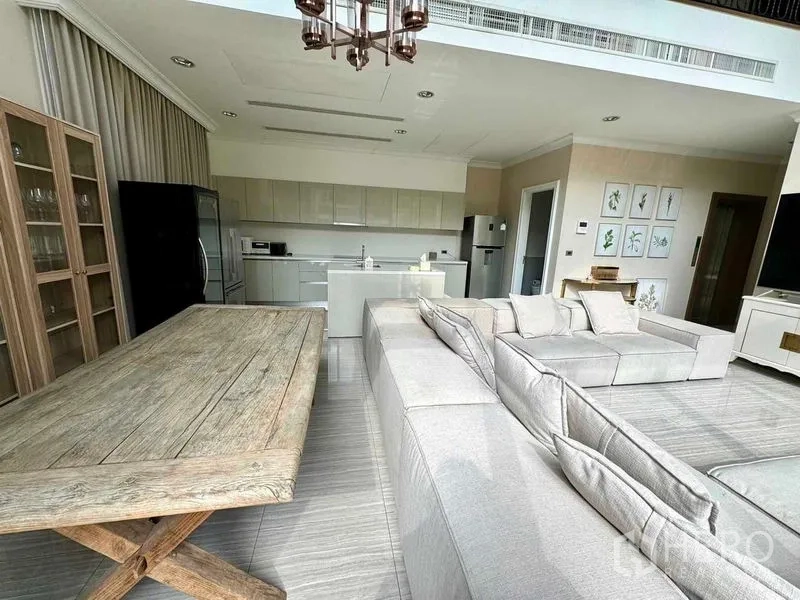 Townhouse for rent in Watthana, Bangkok - Open-plan kitchen with island, dining table and oversized sectional sofa.