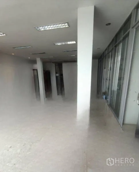 Warehouse for rent in Bang Phli, Samut Prakan - Open-plan office area with floor-to-ceiling glass partition and fluorescent lighting.