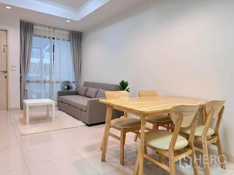 Townhouse for rent in Phra Khanong, Bangkok - Dining area with wooden table set beside a gray sofa.