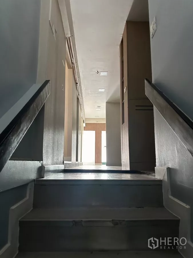 Shophouse for sale in Watthana, Bangkok - Staircase rising to an upper corridor with natural light ahead.