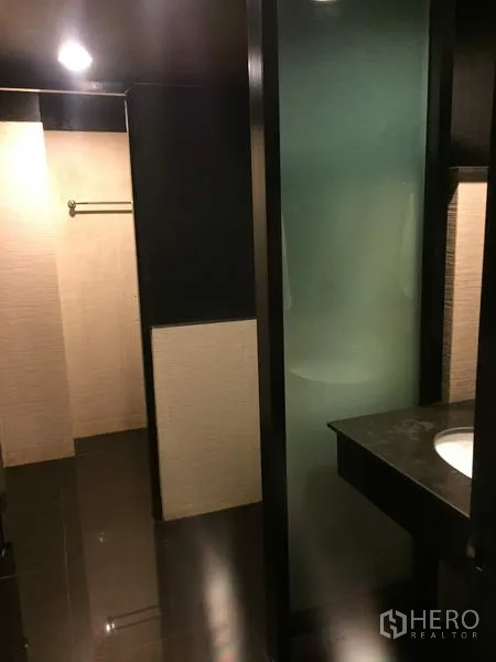 Retail Space for rent in Khlong Toei, Bangkok - Modern bathroom with glass shower partition, stone vanity and dark floor tiles.