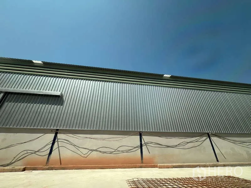 Warehouse for rent in Lat Krabang, Bangkok - Corrugated metal exterior of a modern warehouse with paved loading apron under a clear sky in Lat Krabang, Bangkok.