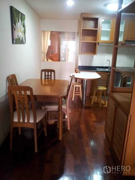 Condominium for rent - Dining space with wooden table and chairs beside a compact kitchenette.