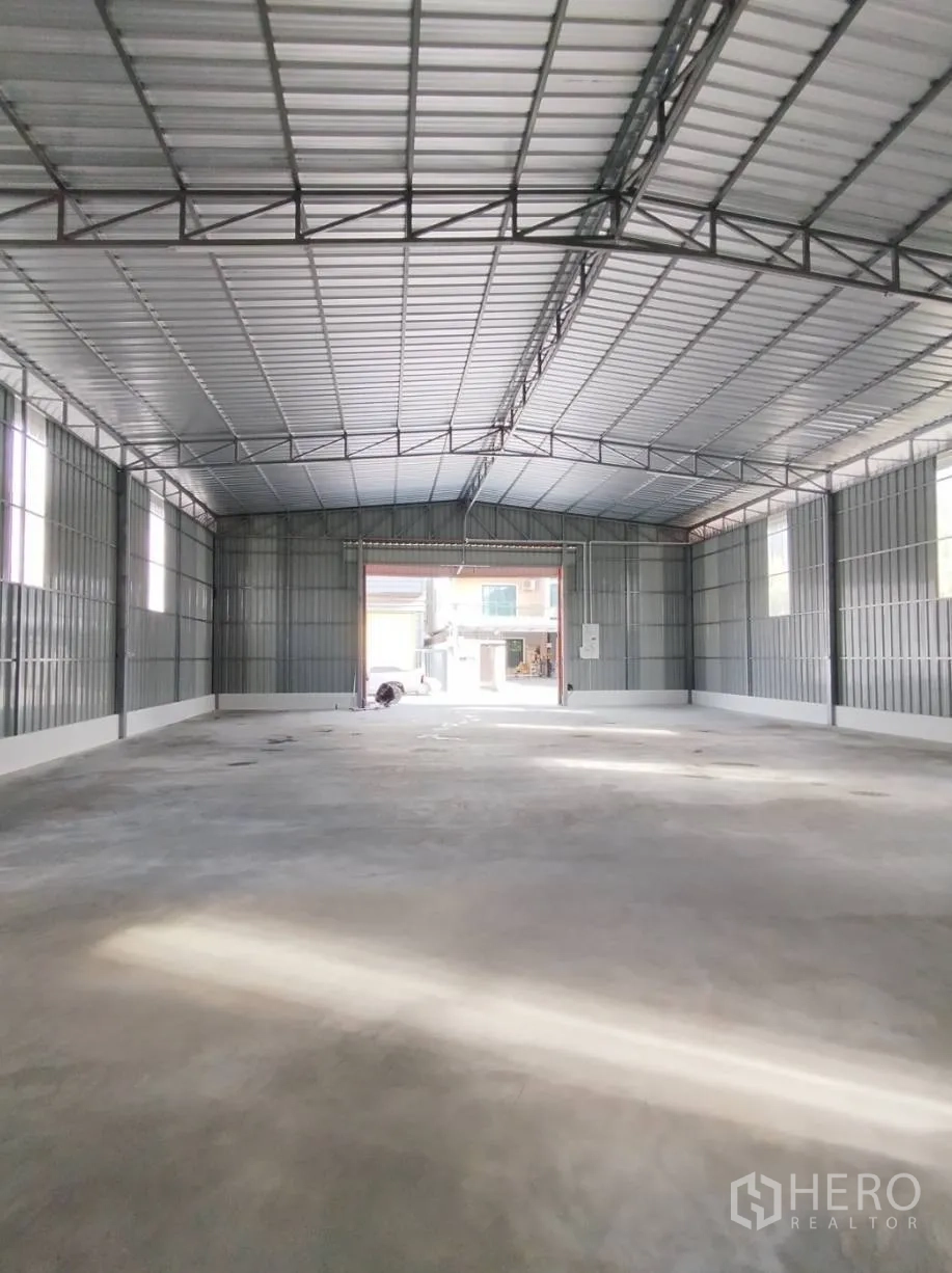 Warehouse for rent in Bang Khen, Bangkok - Spacious open-plan warehouse interior with high steel roof, concrete floor, and large loading opening.