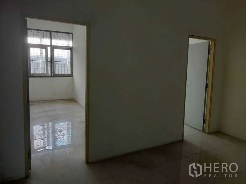 Shophouse for sale in Phra Khanong, Bangkok - Two adjacent rooms with window grilles and natural light.