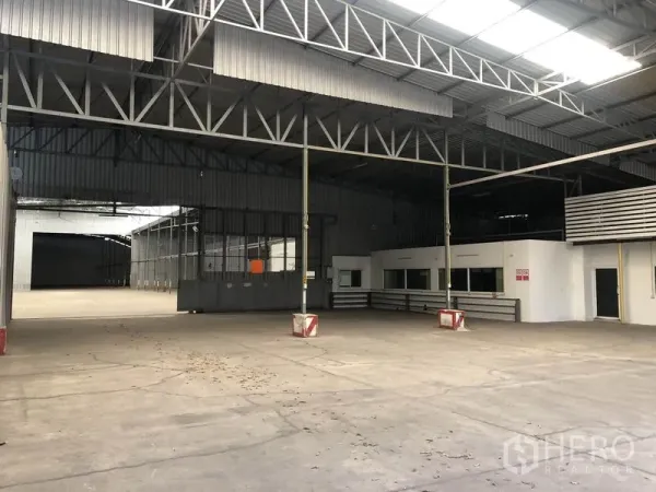 Warehouse for rent in Pak Kret, Nonthaburi - Open storage area showing mezzanine office, partitioned zones, and loading gates inside the warehouse.