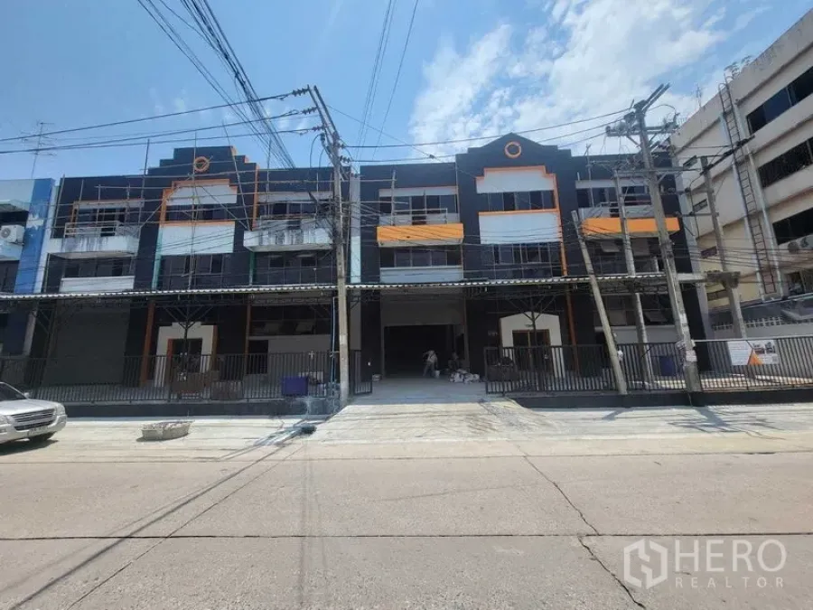 โรงงาน ให้เช่าหรือขายในSamut Prakan - ด้านหน้าอาคารอุตสาหกรรมโทนดำส้มสมัยใหม่ พร้อมทางลาดและรั้ว