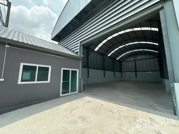 Factory for rent in Pak Kret, Nonthaburi - Close-up of the office unit with glass door and windows beside the large warehouse entrance.