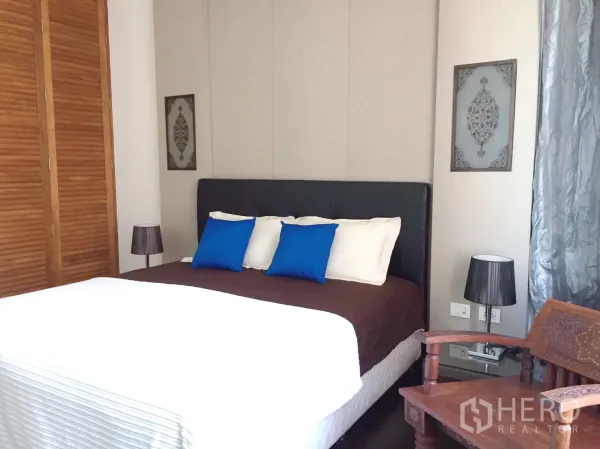 Condominium for rent in Khlong Toei, Bangkok - Master bedroom with upholstered bed, wooden closet doors and bedside lamps