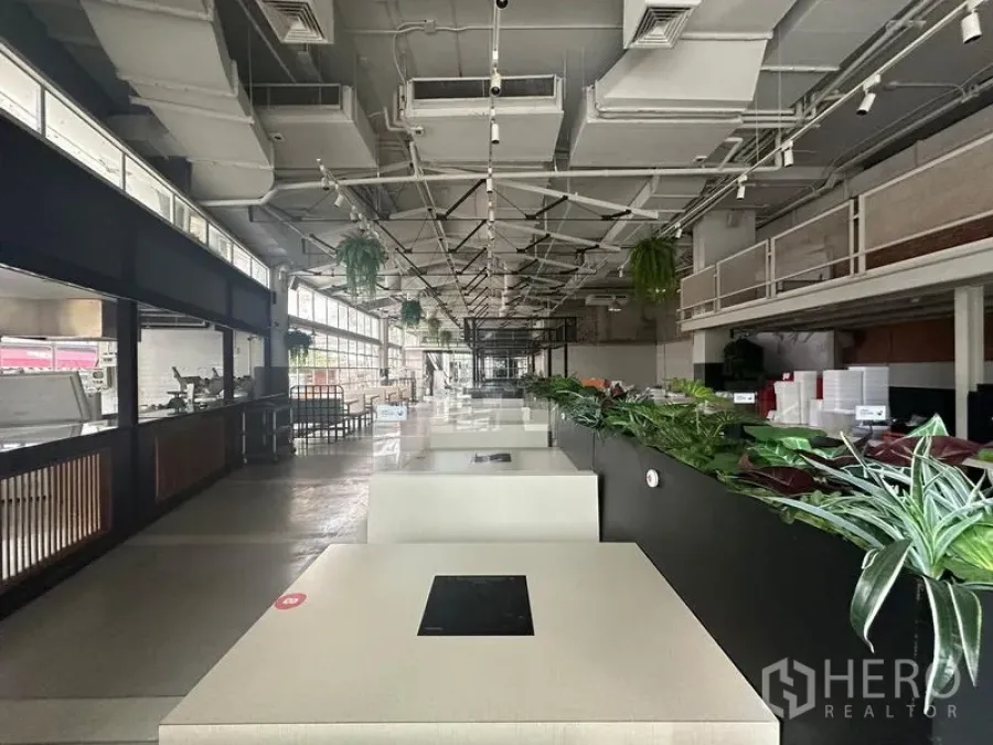 零售空间 出租在Watthana, Bangkok - 沿大厅纵深的视角，桌椅、绿植和大面积窗户。