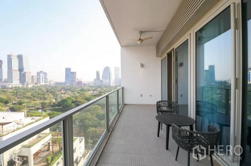 Condominium for rent in Pathum Wan, Bangkok - Spacious balcony with seating and glass railing overlooking the park and skyline.