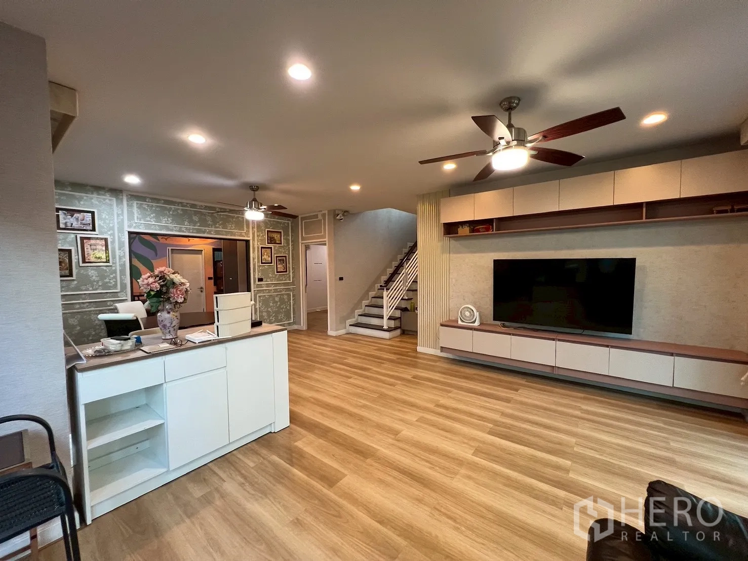 Detached House for rent in Bang Kapi, Bangkok - Large living room with built-in TV wall, ceiling fans, and light wood flooring.