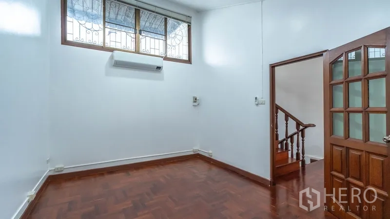 Townhouse for rent in Khlong Toei, Bangkok - Room with wooden door, parquet floor and high windows with patterned grilles.