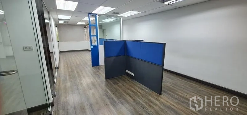 Office Space for rent in Watthana, Bangkok - Long workspace with blue dividers, wood floors, and ceiling lights.