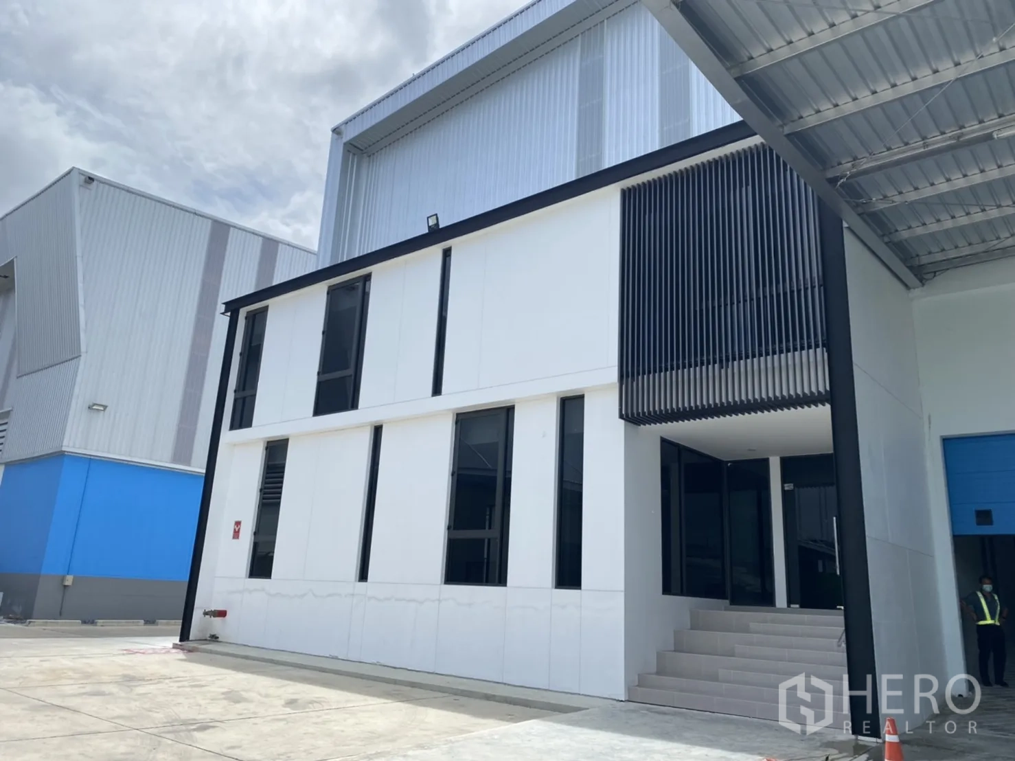 货栈 出租在Chachoengsao - 仓库旁两层现代办公楼，带立面格栅遮阳。