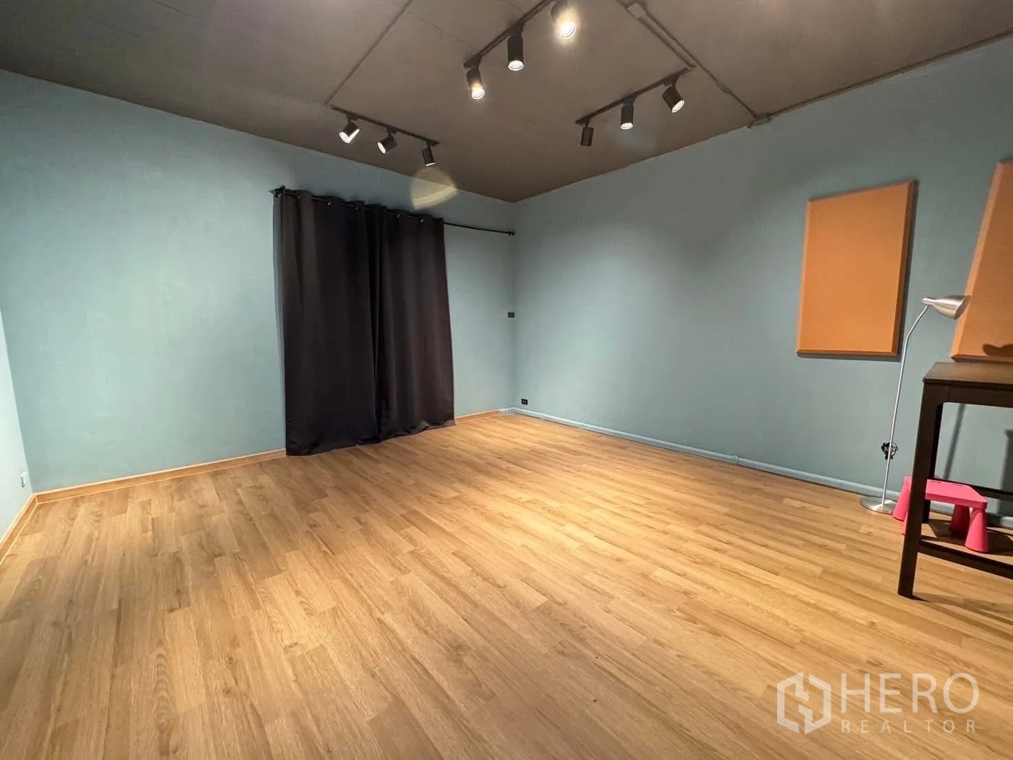 Home Office for rent in Watthana, Bangkok - Spacious studio-style room with wood flooring, blue walls and track lighting.