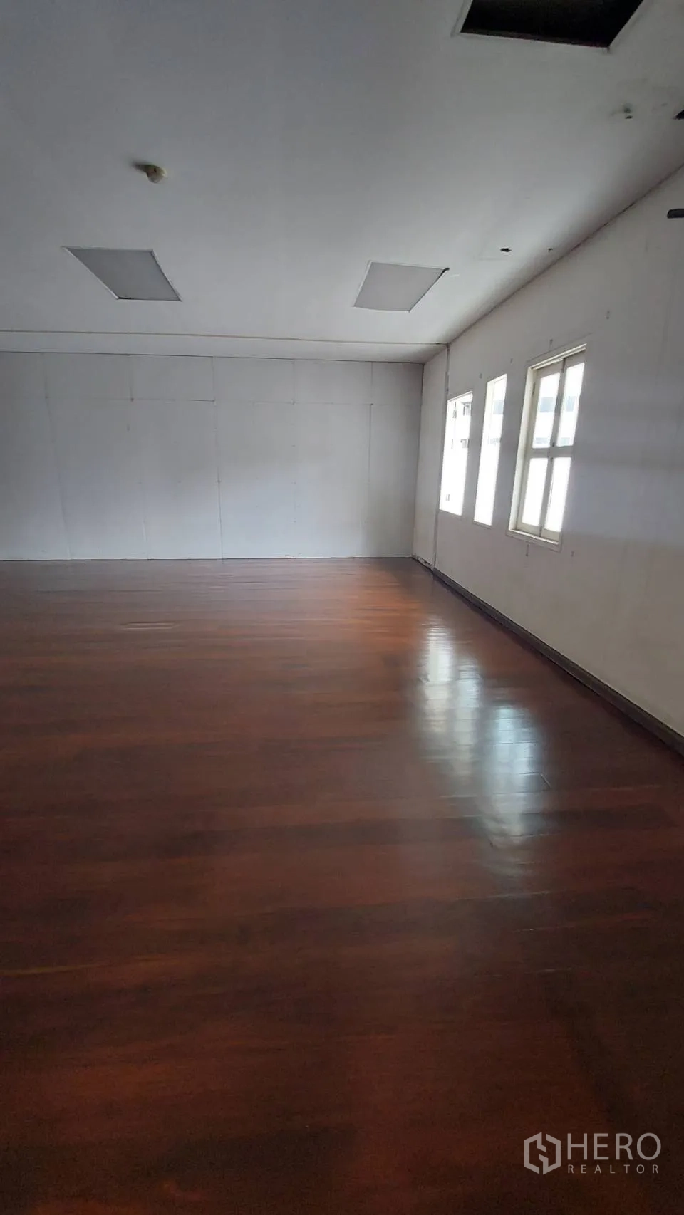 Office Space for rent in Watthana, Bangkok - Spacious office interior with multiple windows, white walls and dark hardwood flooring.