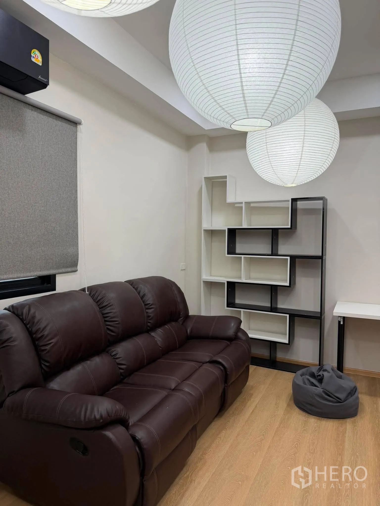 Home Office for rent in Phra Khanong, Bangkok - Lounge corner with dark leather sofa and display shelves.