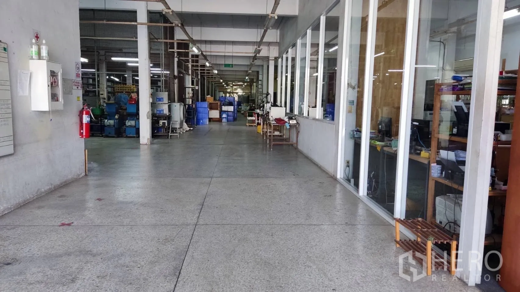 Factory for sale in Lat Krabang, Bangkok - Wide corridor beside glass-front offices with safety equipment on the wall.