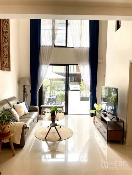 Townhouse for rent in Suan Luang, Bangkok - Double-height lounge facing sliding doors that open to the patio and garden.