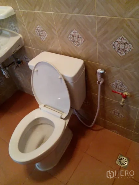 Shophouse for rent in Phra Khanong, Bangkok - Close-up of toilet with handheld bidet and floor drain.
