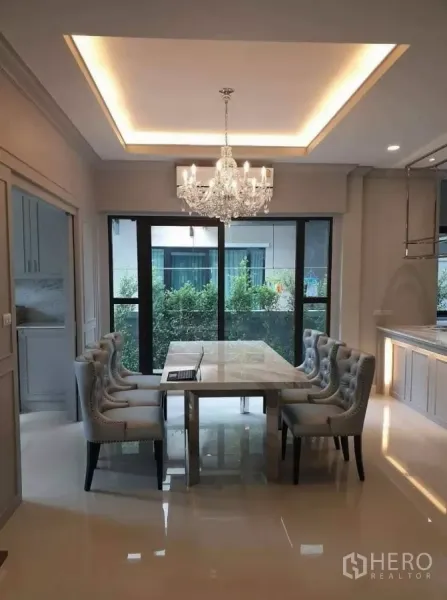 Detached House for rent or sale in Prawet, Bangkok - Dining area with crystal chandelier, marble table and garden-view sliding doors