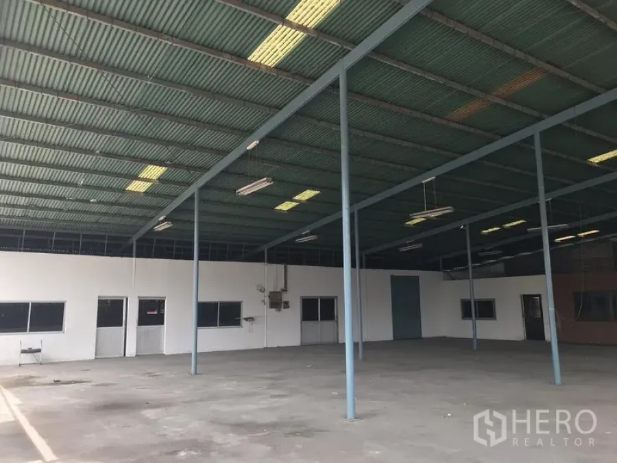 货栈 出租在Bang Phli, Samut Prakan - 开阔的仓库内部，高钢结构屋顶带采光板与吊灯，混凝土地面，侧设办公室。