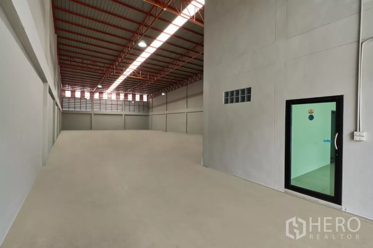 Factory for rent in Mueang Samut Sakhon, Samut Sakhon - Spacious warehouse interior with smooth concrete floor and side glass door to the office.