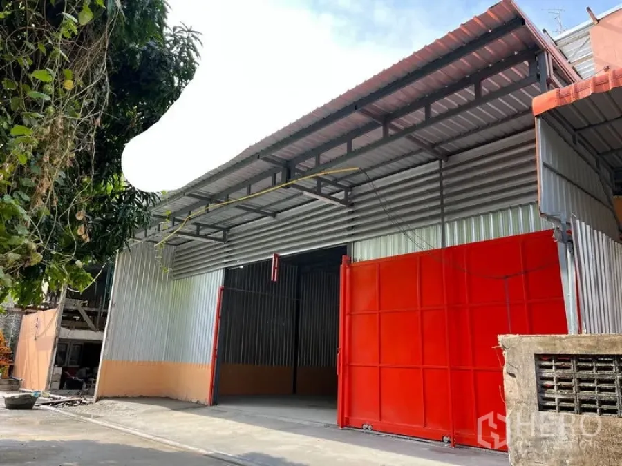 Warehouse for rent in Din Daeng, Bangkok - Metal-clad warehouse exterior with wide red sliding gates and a covered loading bay.