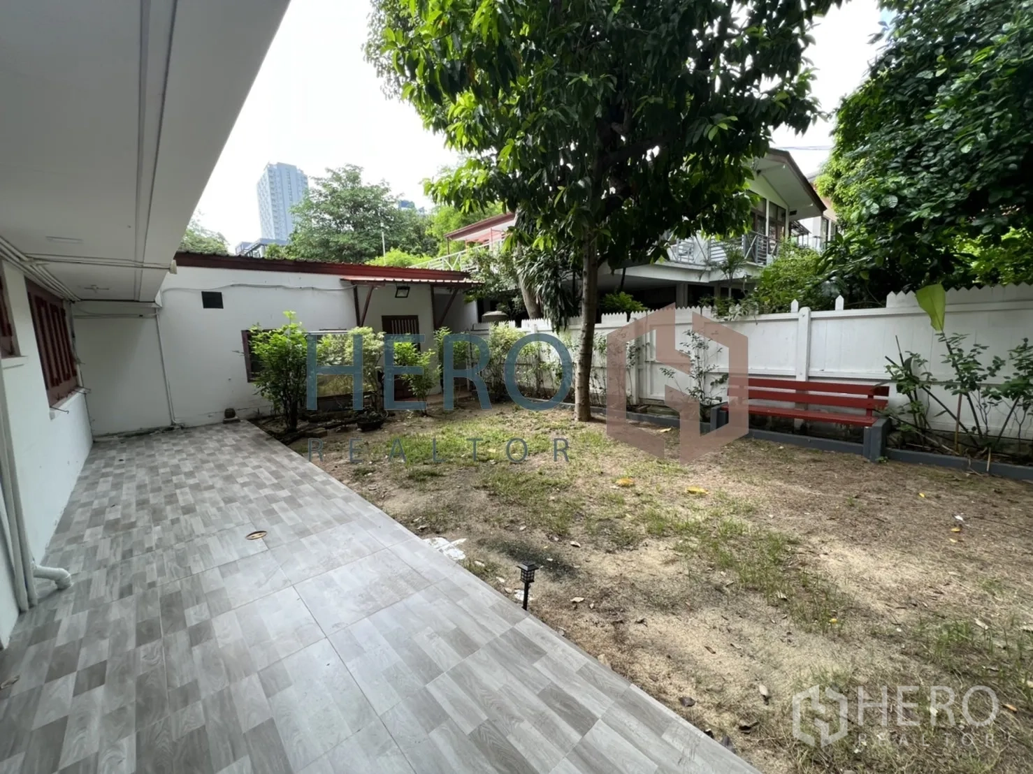 Detached House for rent in Watthana, Bangkok - Fenced backyard with a mature tree, bench and lawn.