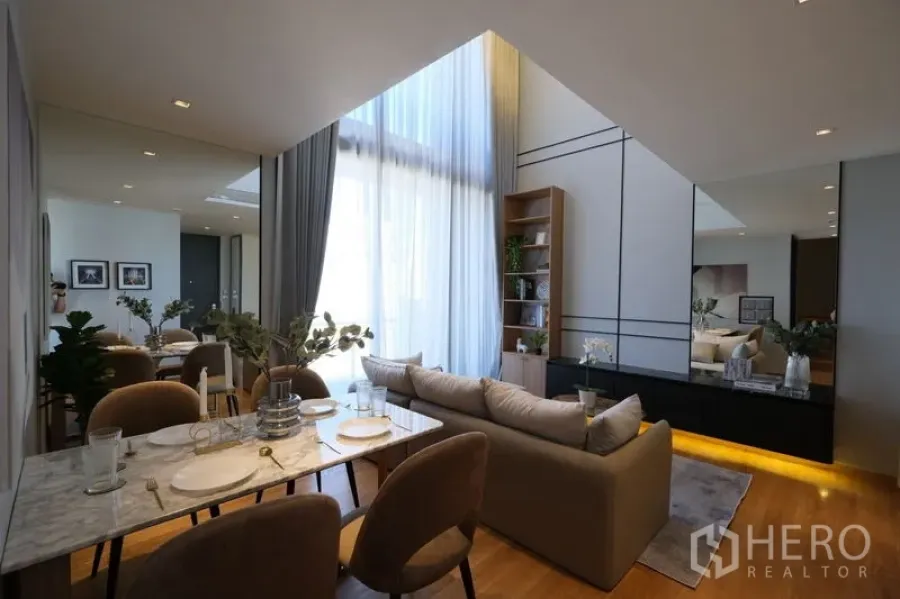 Condominium for rent - Stylish living-dining room with high windows, marble table, and illuminated media console.
